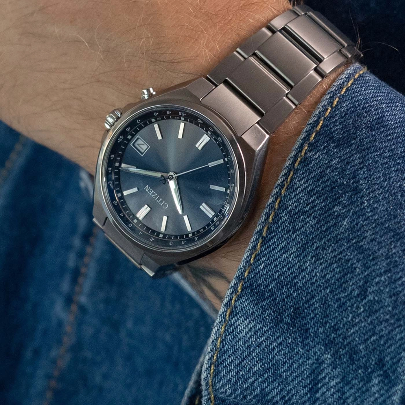 A man wears a Citizen watch on his wrist, showing the dial and metal band.