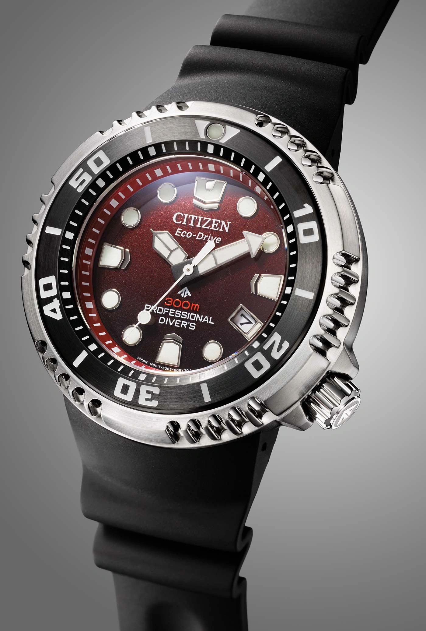 Close-up of a Citizen Eco-Drive watch with a red dial and black strap.