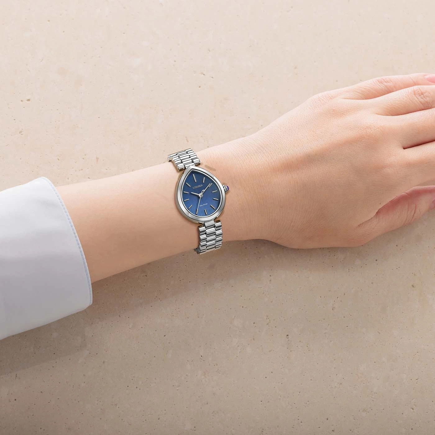 A woman's wrist wearing a silver watch with a blue face.
