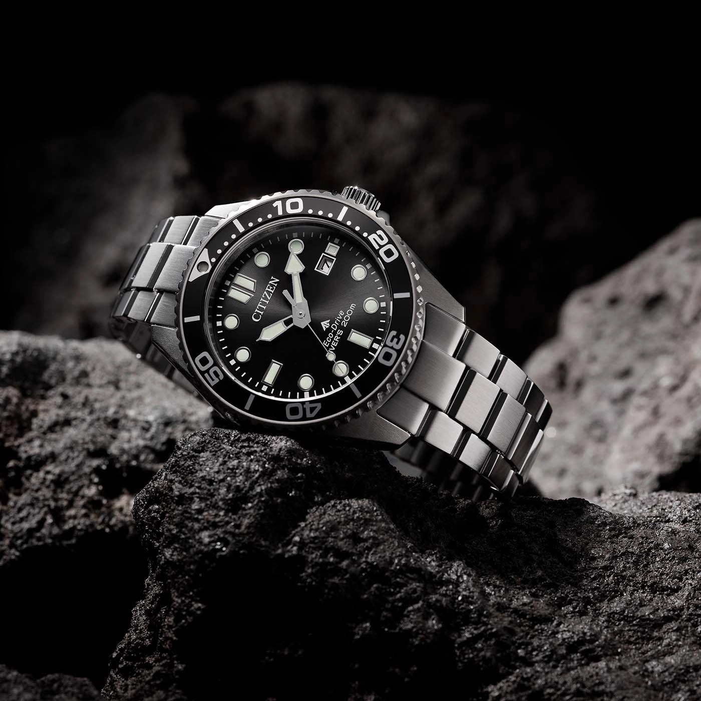 Citizen watch on a rock. Black dial, silver band. Eco-Drive, divers 200m.