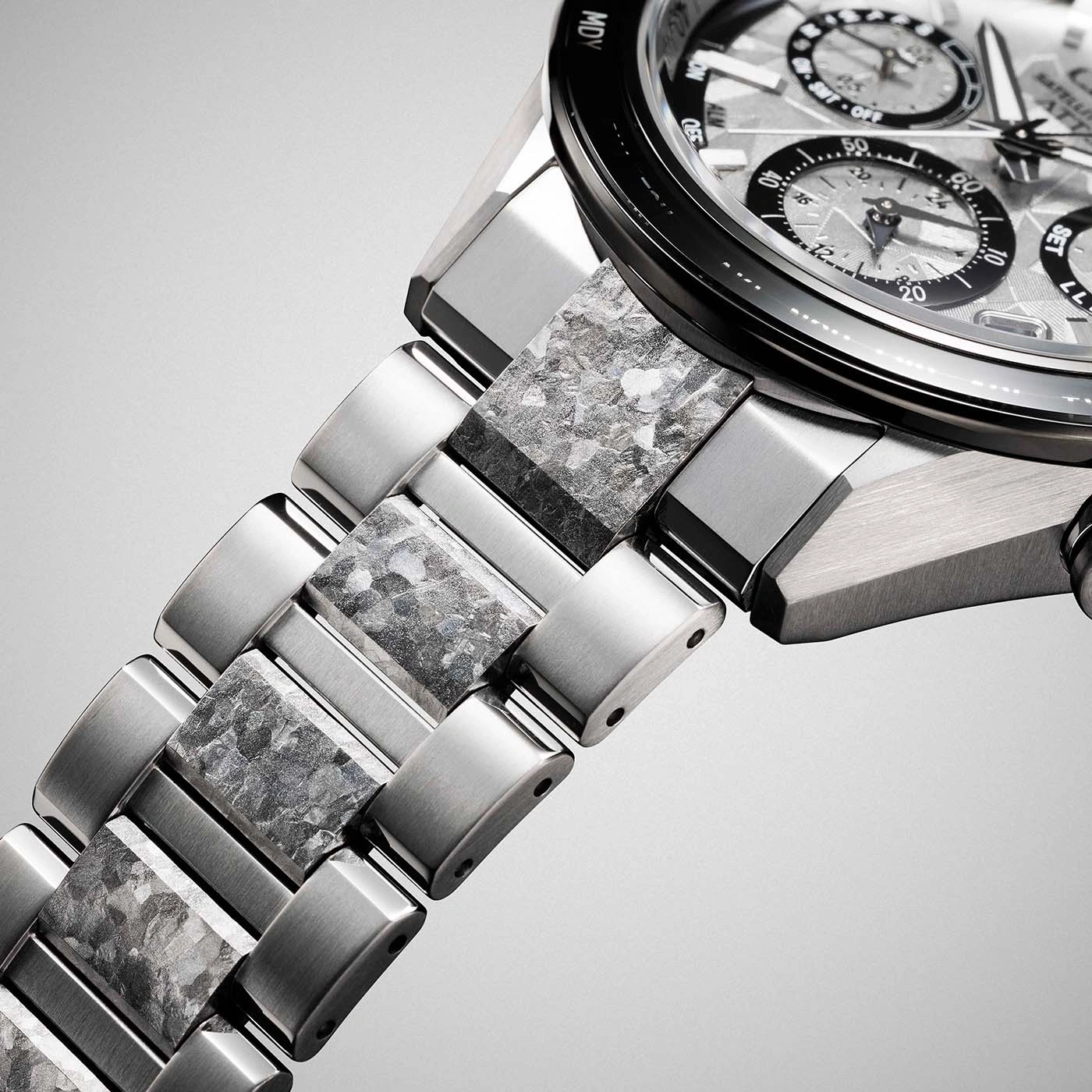 Close-up of a luxury watch band with textured stone and metal links.