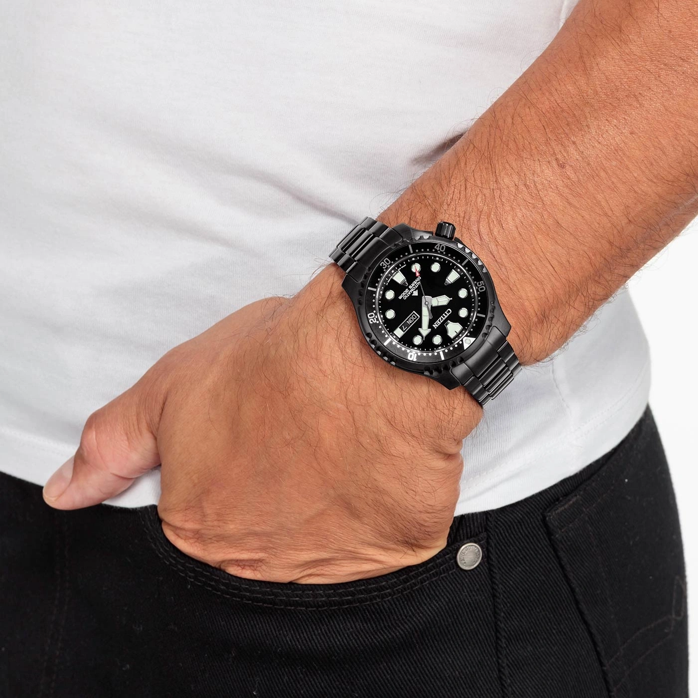 Man wearing a black watch, white shirt, and black jeans. Wristwatch detail.