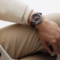Man wearing a Citizen watch with a brown leather strap and a brown dial.