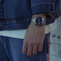Man wearing a blue denim jacket, white t-shirt and jeans with a watch