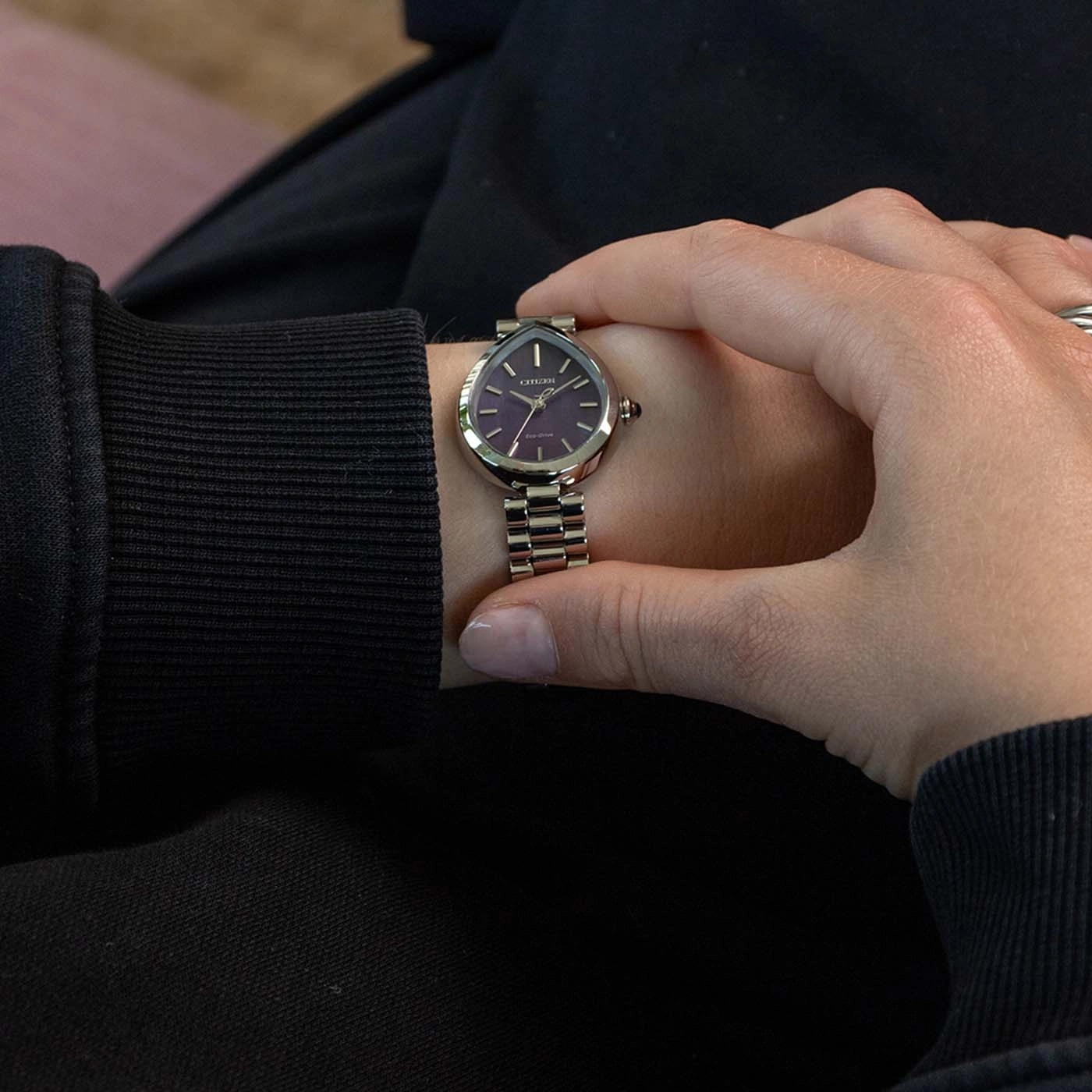 A woman checks her wrist watch with a purple face.
