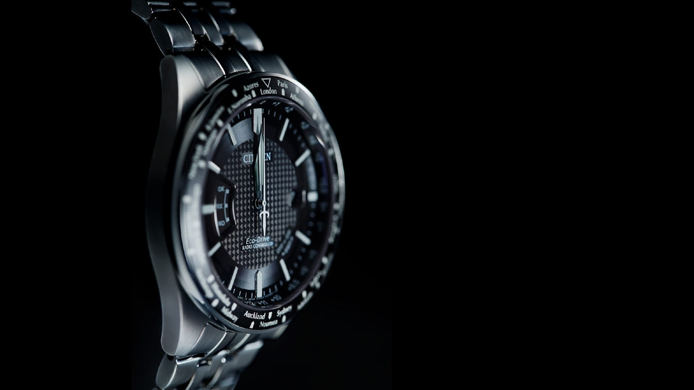 Close-up of a Citizen watch with a black face and silver band, time zones.