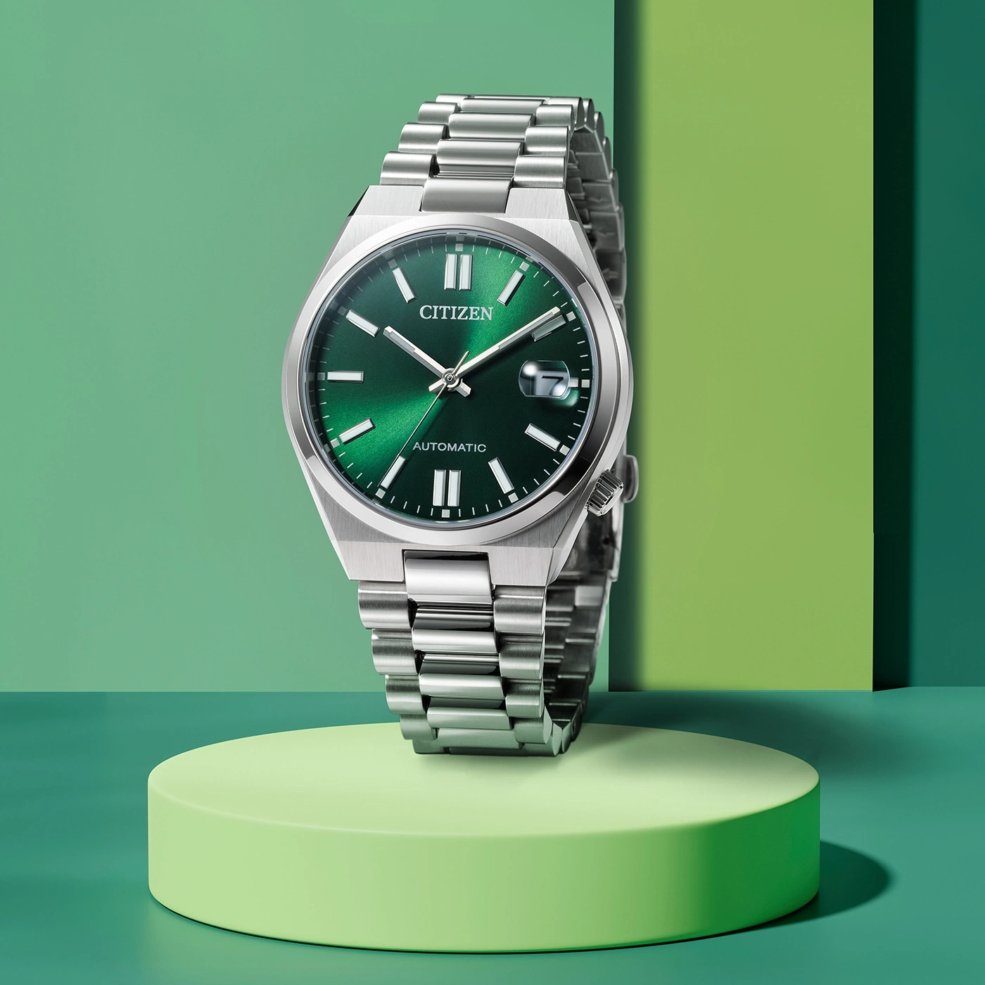 Citizen watch with green face and silver band on a green platform.