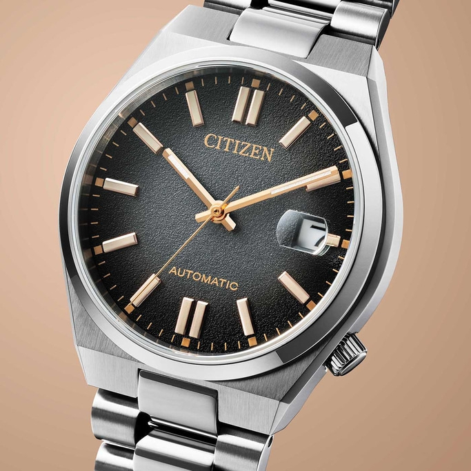 Citizen automatic watch with black face and silver bracelet, close-up.