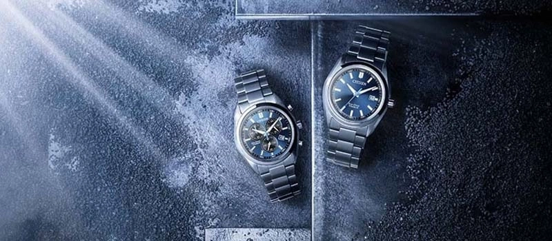 Two Citizen watches with blue dials on a textured background