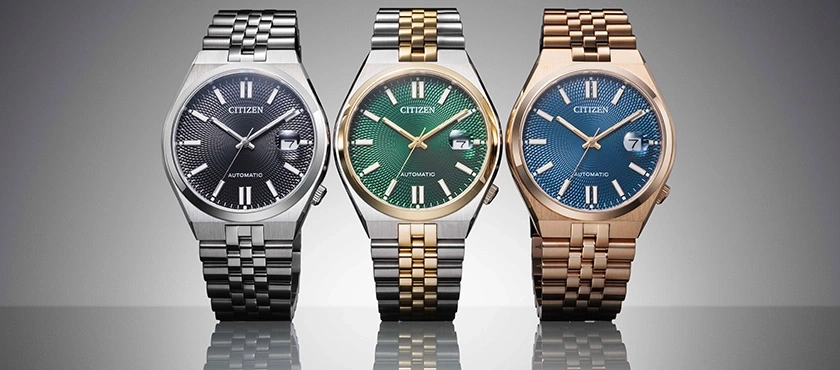 Three Citizen watches with different colored faces and metal bands.
