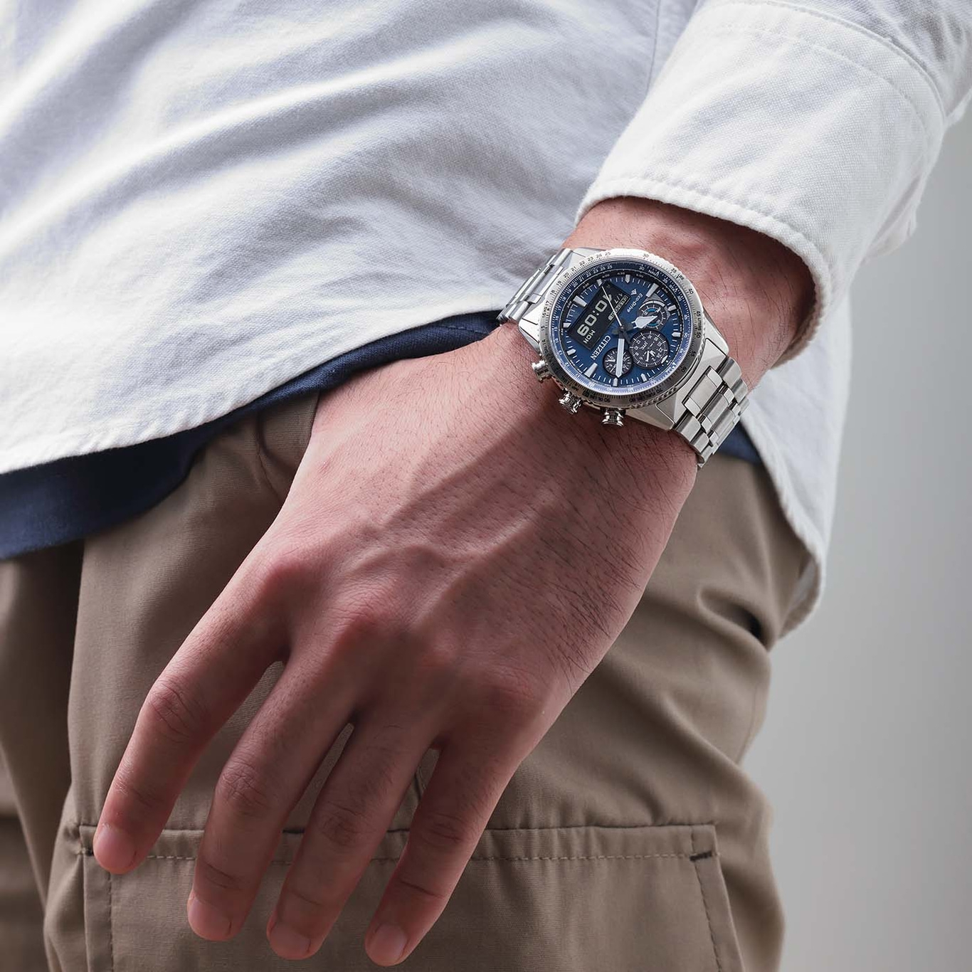 Man wearing a silver watch with a blue face and a white shirt.