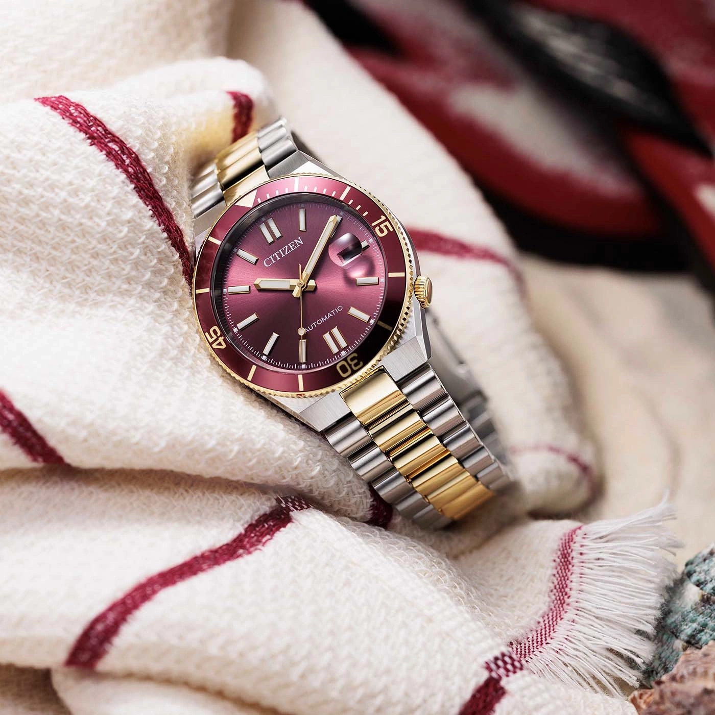 A close-up shot of a Citizen automatic watch with a red dial and gold accents.