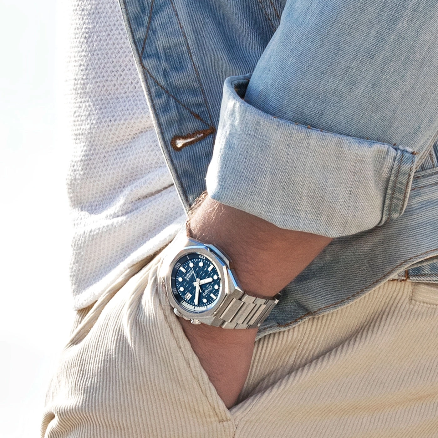 Man wearing a watch, denim jacket, and corduroy pants, close-up shot