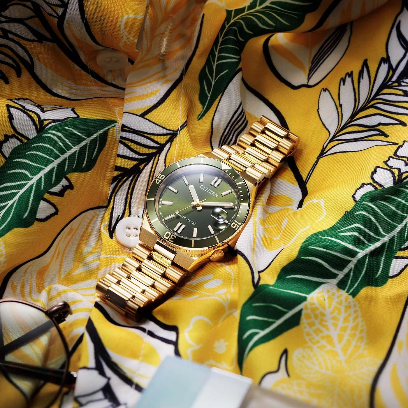 A gold Citizen watch on a yellow floral shirt.