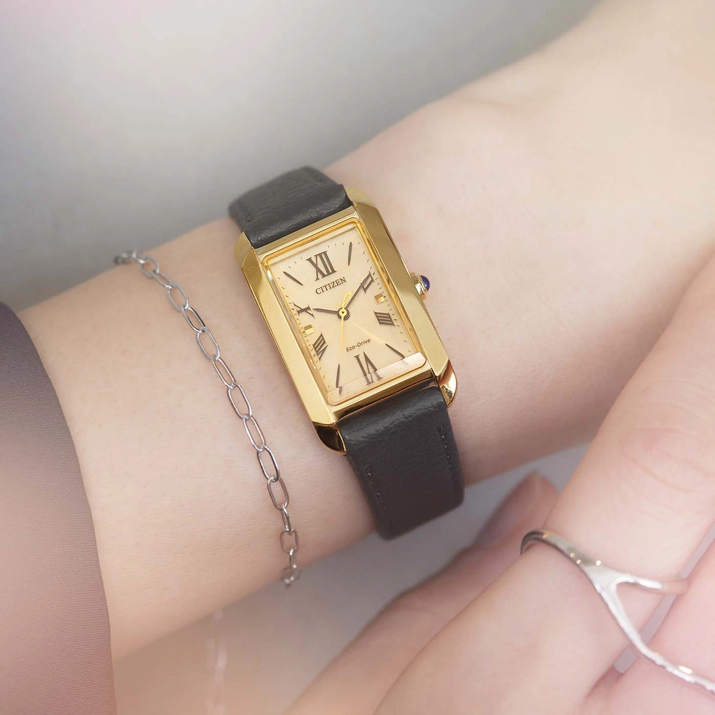 Gold watch on wrist with black strap and silver bracelet