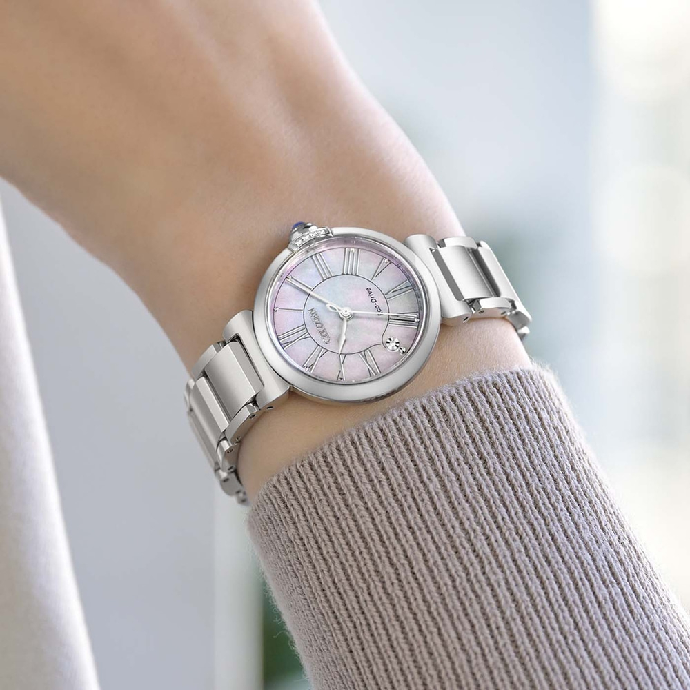 A woman's wrist wearing a silver watch with a mother-of-pearl dial.