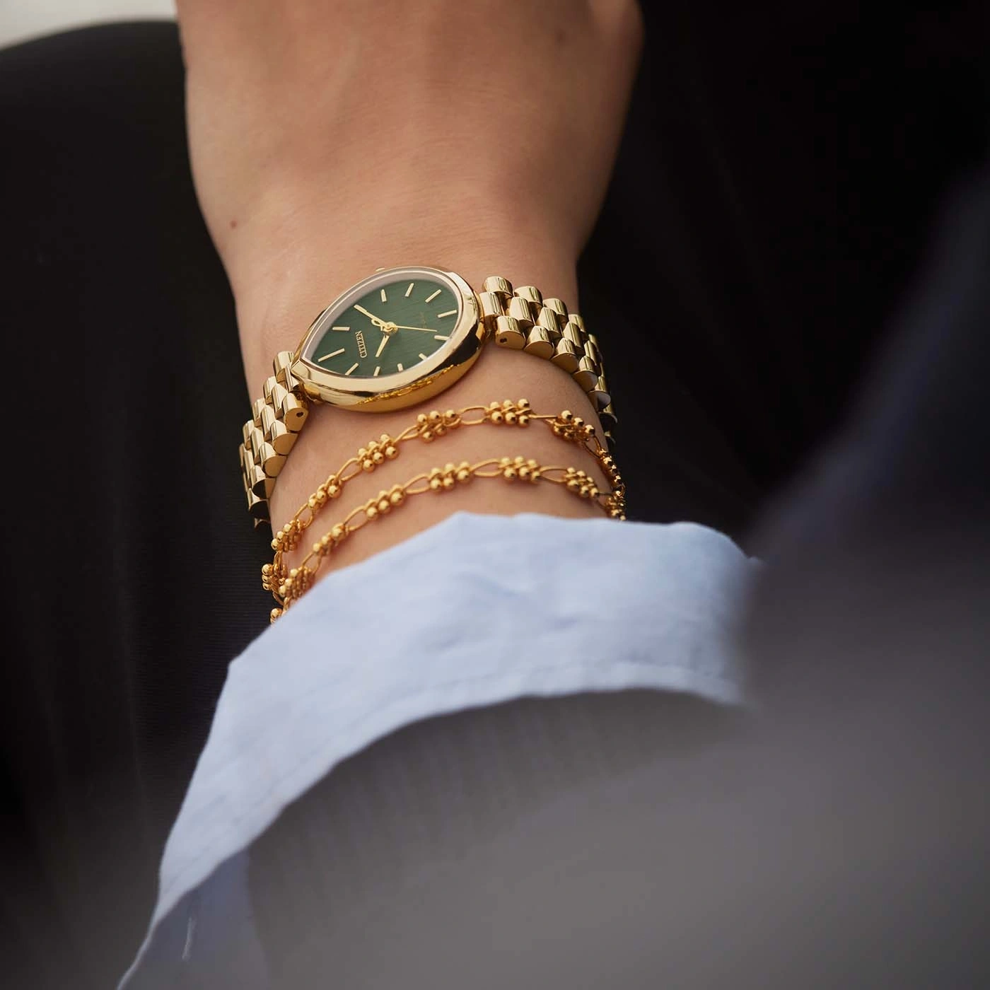 A gold watch and bracelets on a woman's wrist