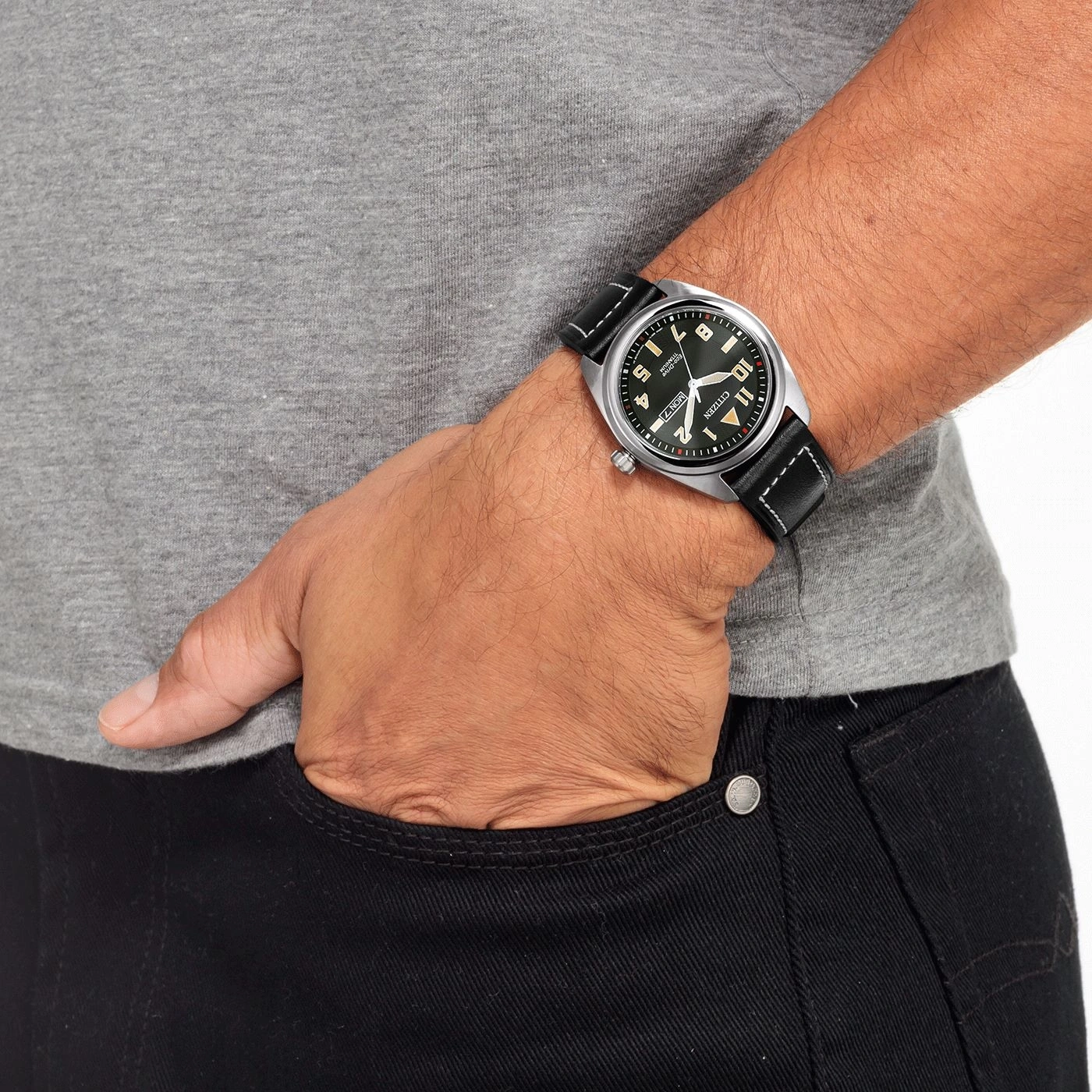 Man wearing a watch, hand in pocket, gray shirt, black jeans, close-up shot