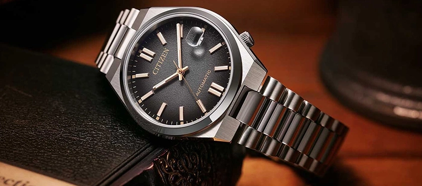Citizen watch with a black dial and silver bracelet on a book