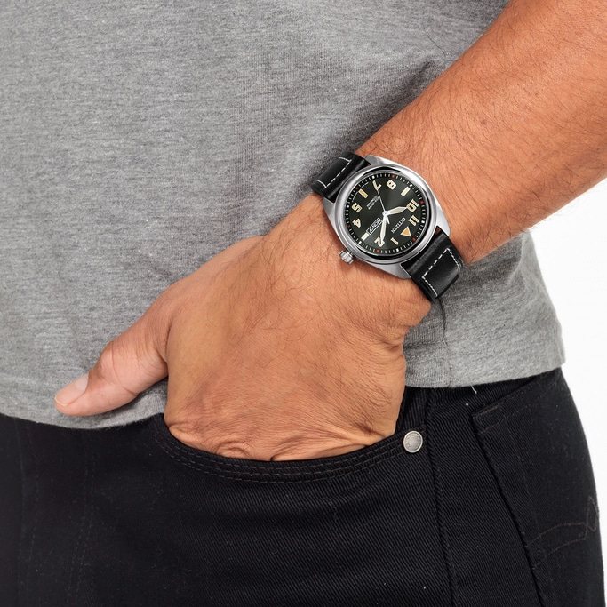 Man wearing a watch, hand in pocket, gray shirt, black jeans, close-up shot