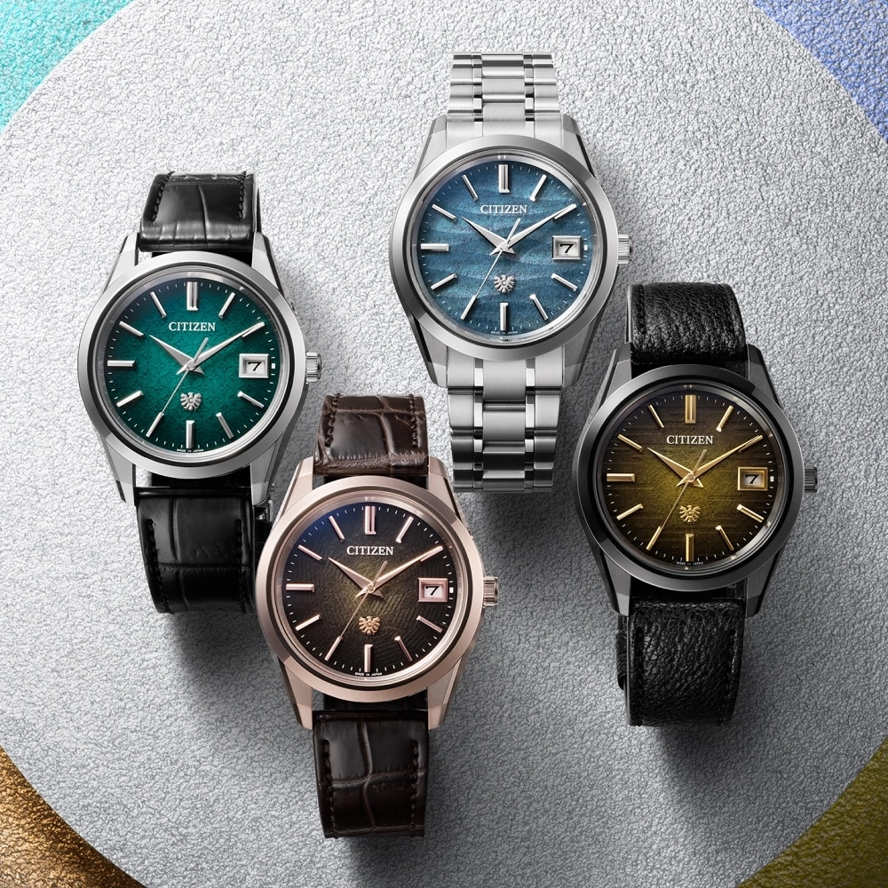 Four Citizen watches with different colored faces and straps on a silver surface.