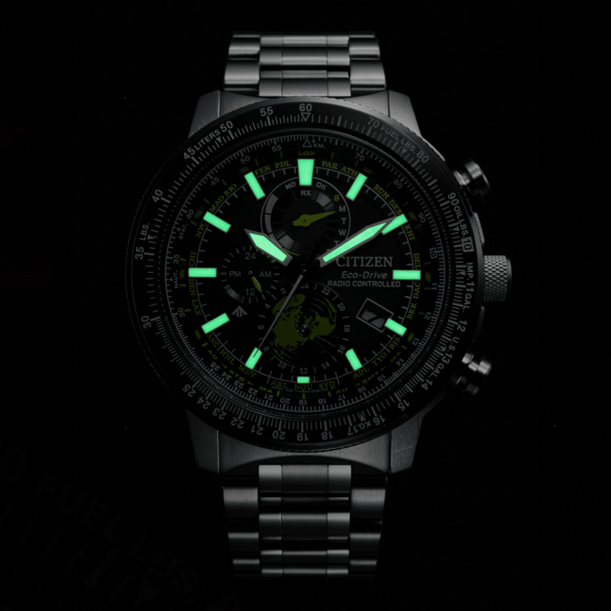 Citizen Eco-Drive watch with glowing hands and markers, black background, time display.