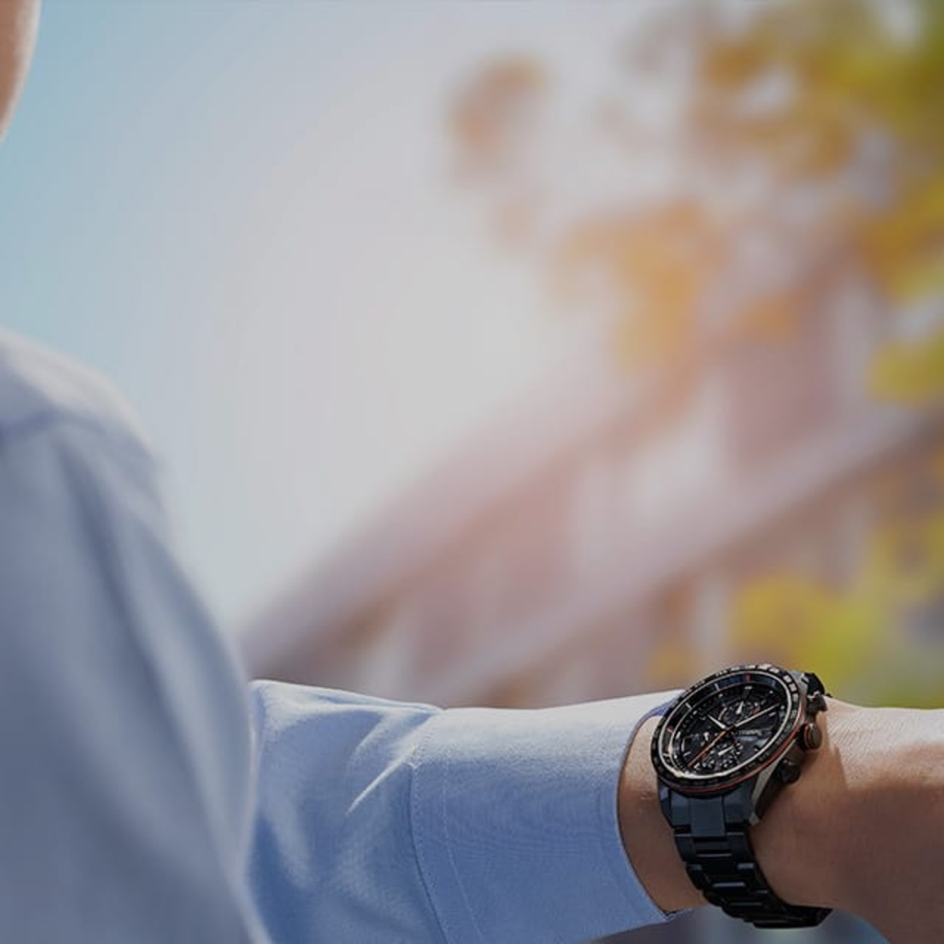 Man wearing a black watch, blue shirt, outdoors, sunny day, wrist watch
