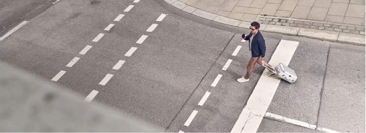 Man with suitcase crossing the street at a crosswalk