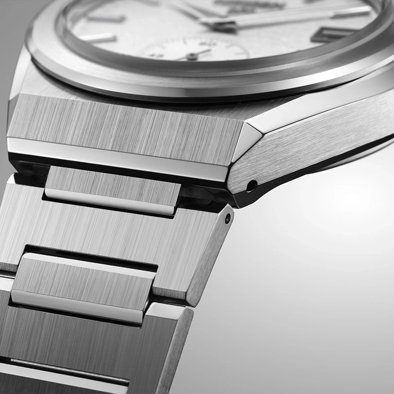 Close-up of a silver watch with a brushed metal finish and a white face.