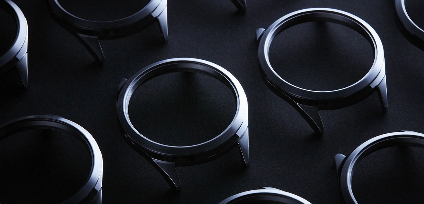 Watch components arranged on a dark surface, showcasing design and detail.