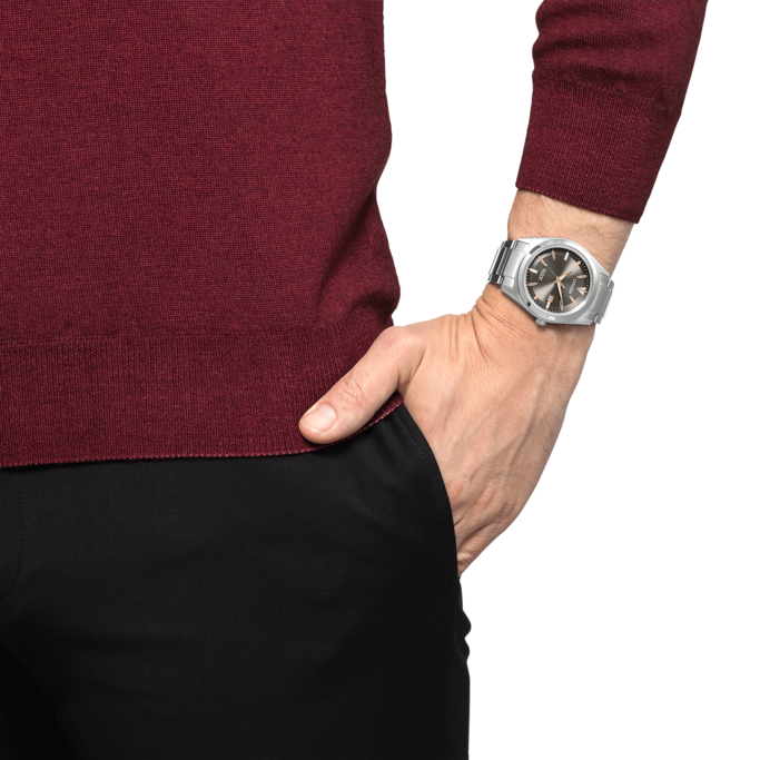 Man wearing a watch, hand in pocket, burgundy sweater, black pants.