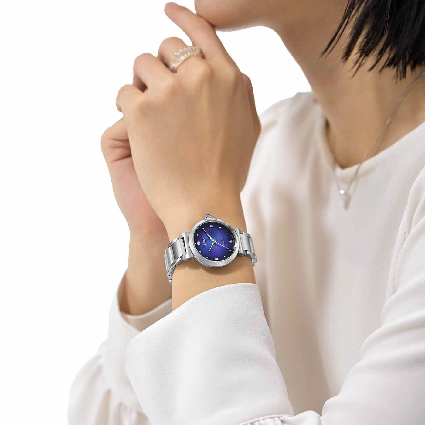 Woman wearing a silver watch with a blue face and diamonds