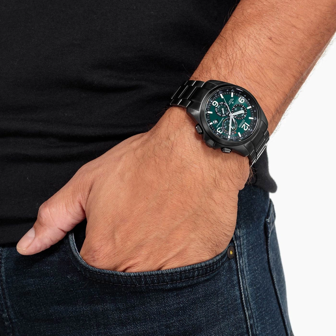 Man wearing a black watch with a green face, hand in pocket.