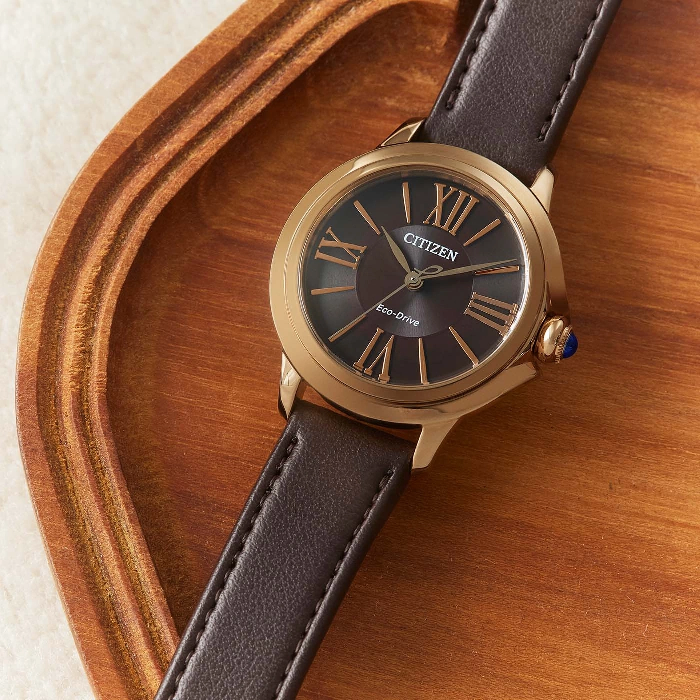 Citizen watch with brown leather strap on wooden tray