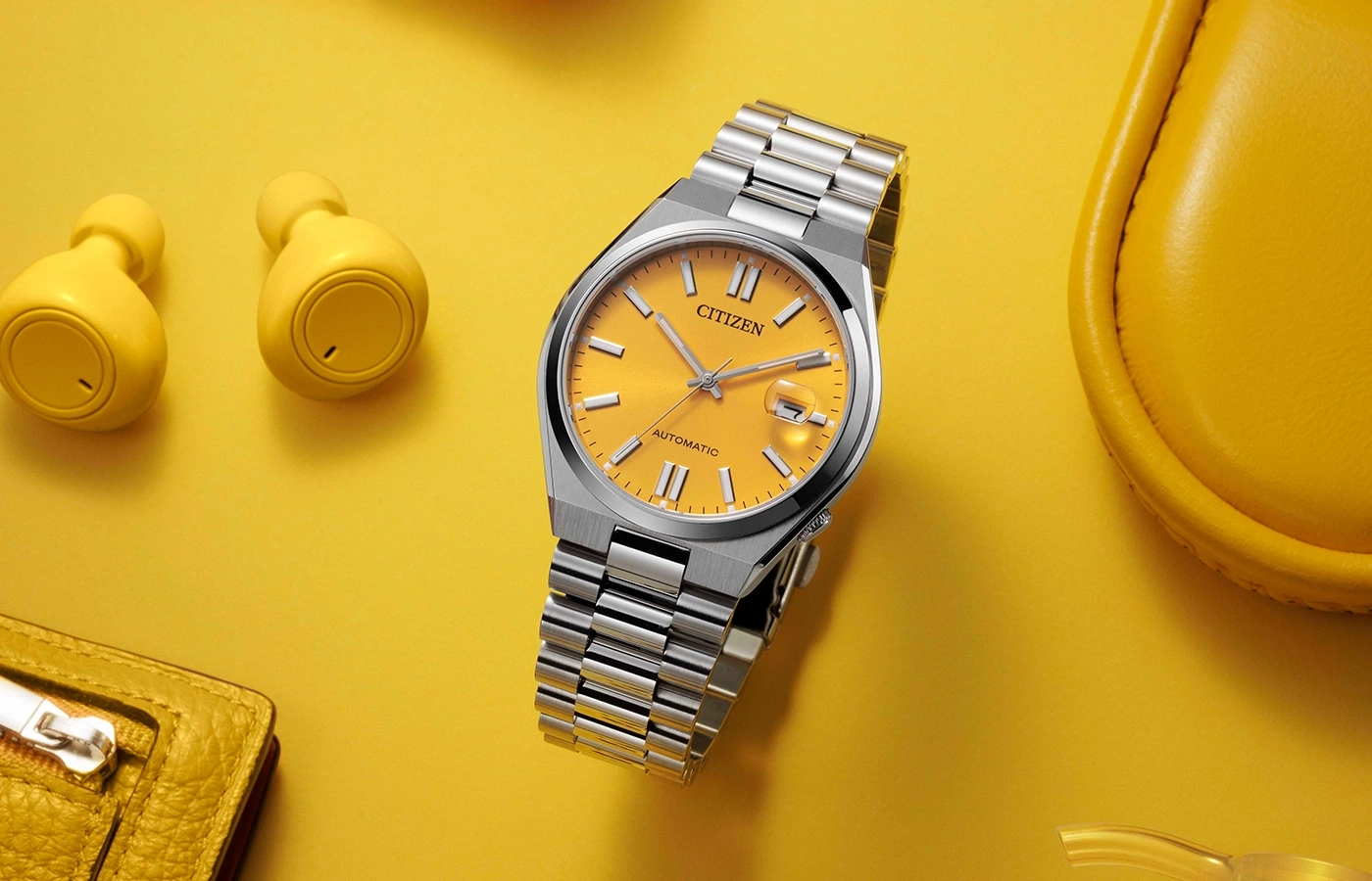 Citizen watch, yellow background, earbuds, wallet, and a yellow bag.