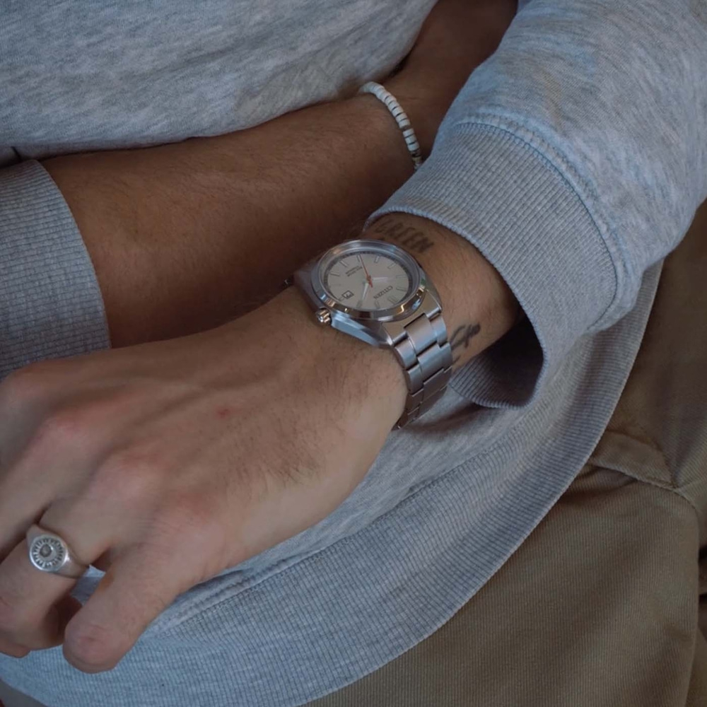 A close-up shot of a man's arm with a watch and ring.