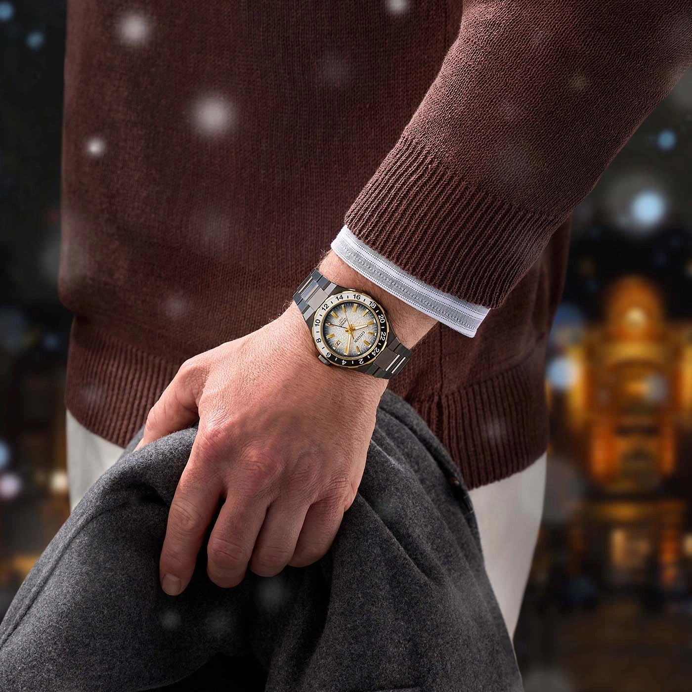 Man wearing a watch, holding a coat, with a blurred background.
