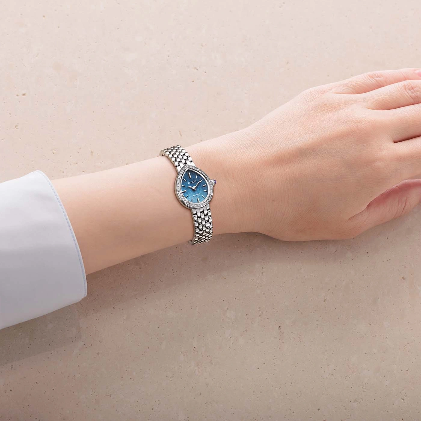 Woman's wrist wearing a diamond-accented teardrop watch.