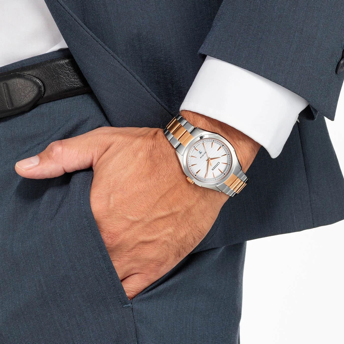 Man wearing a Citizen watch, suit, and white shirt, hand in pocket.