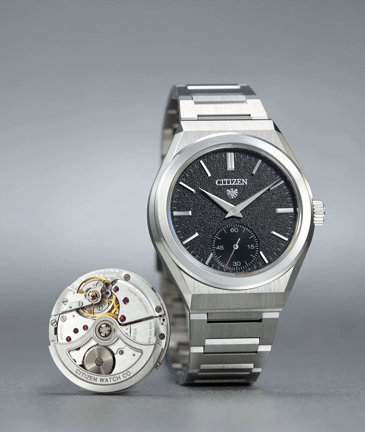 Citizen watch with exposed mechanism, black dial, silver bracelet, and intricate details.