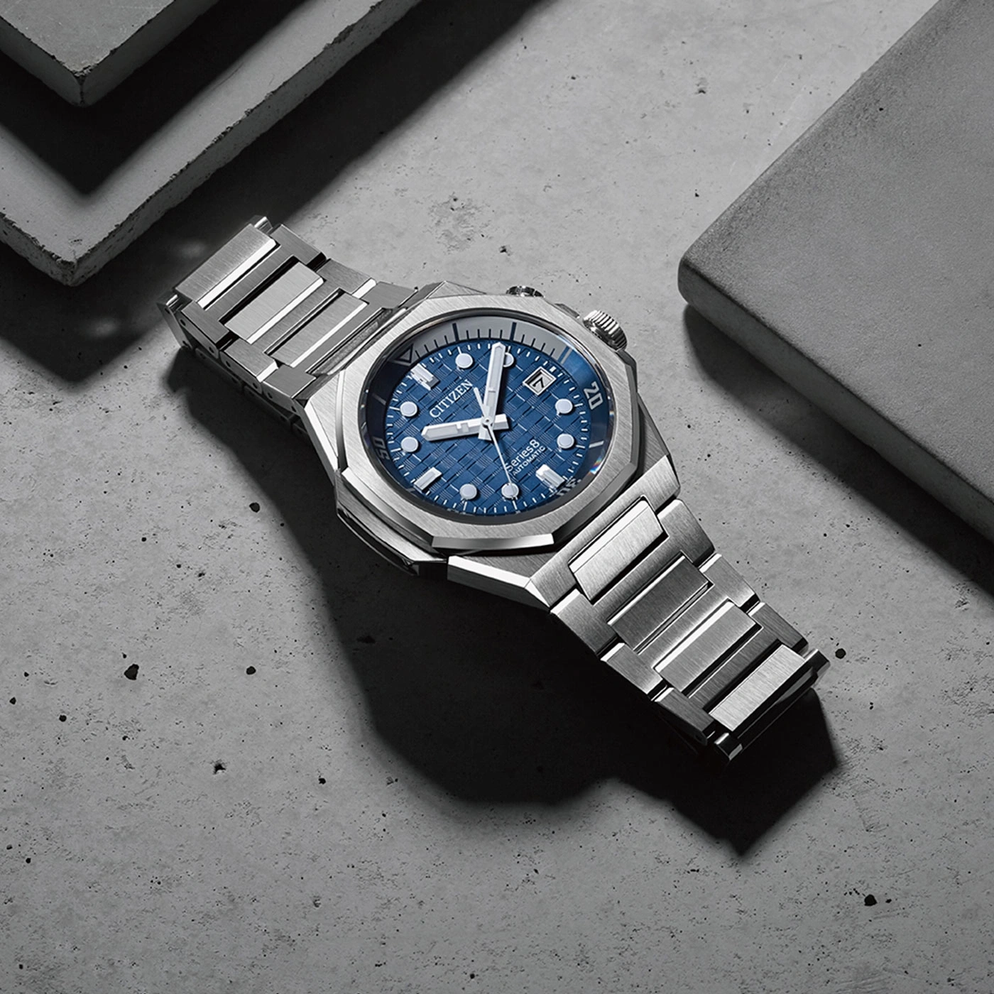 Citizen watch with blue face and silver strap on concrete surface
