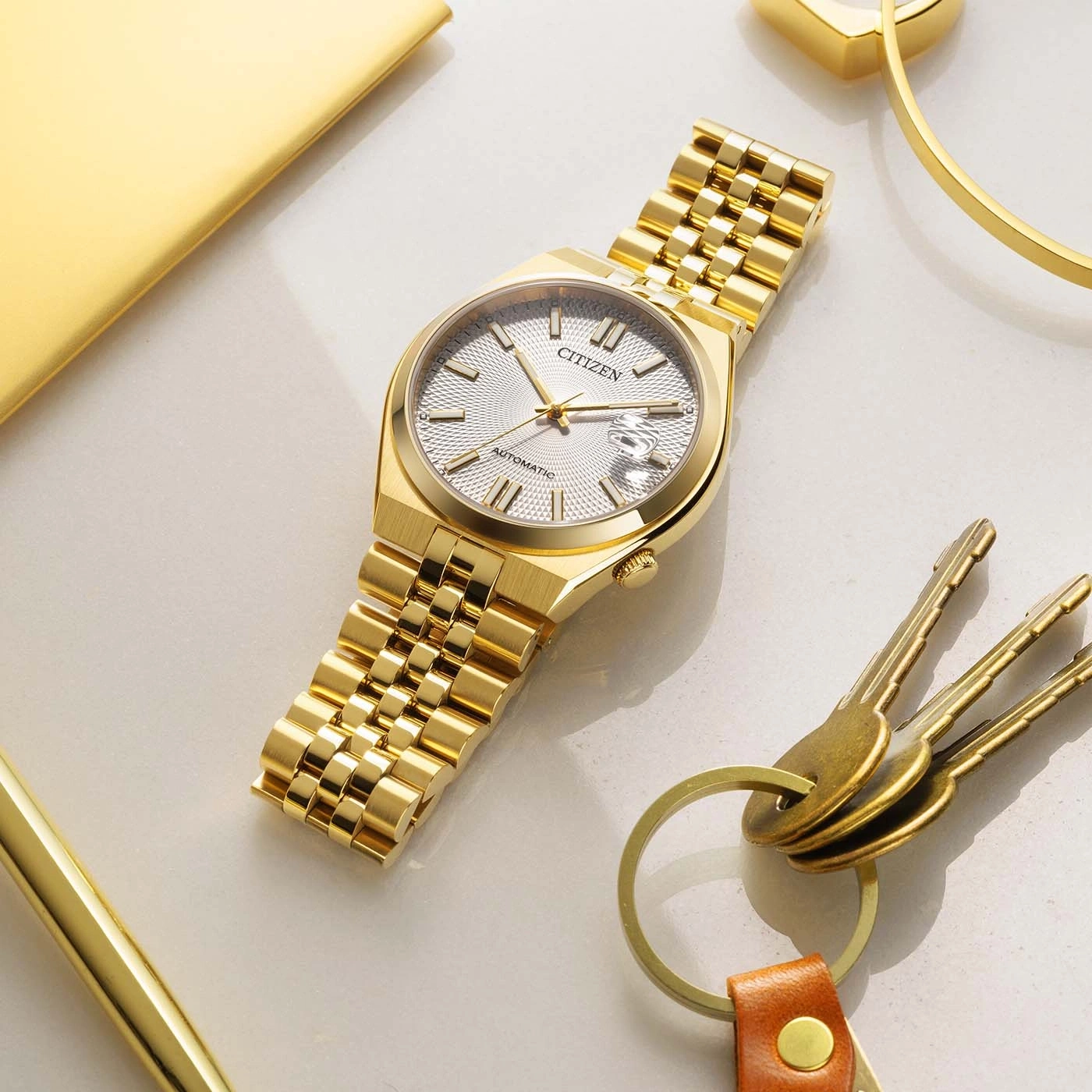 A gold Citizen automatic watch with a textured dial and date window.