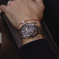 Man's wrist with a watch and a smiley bracelet.