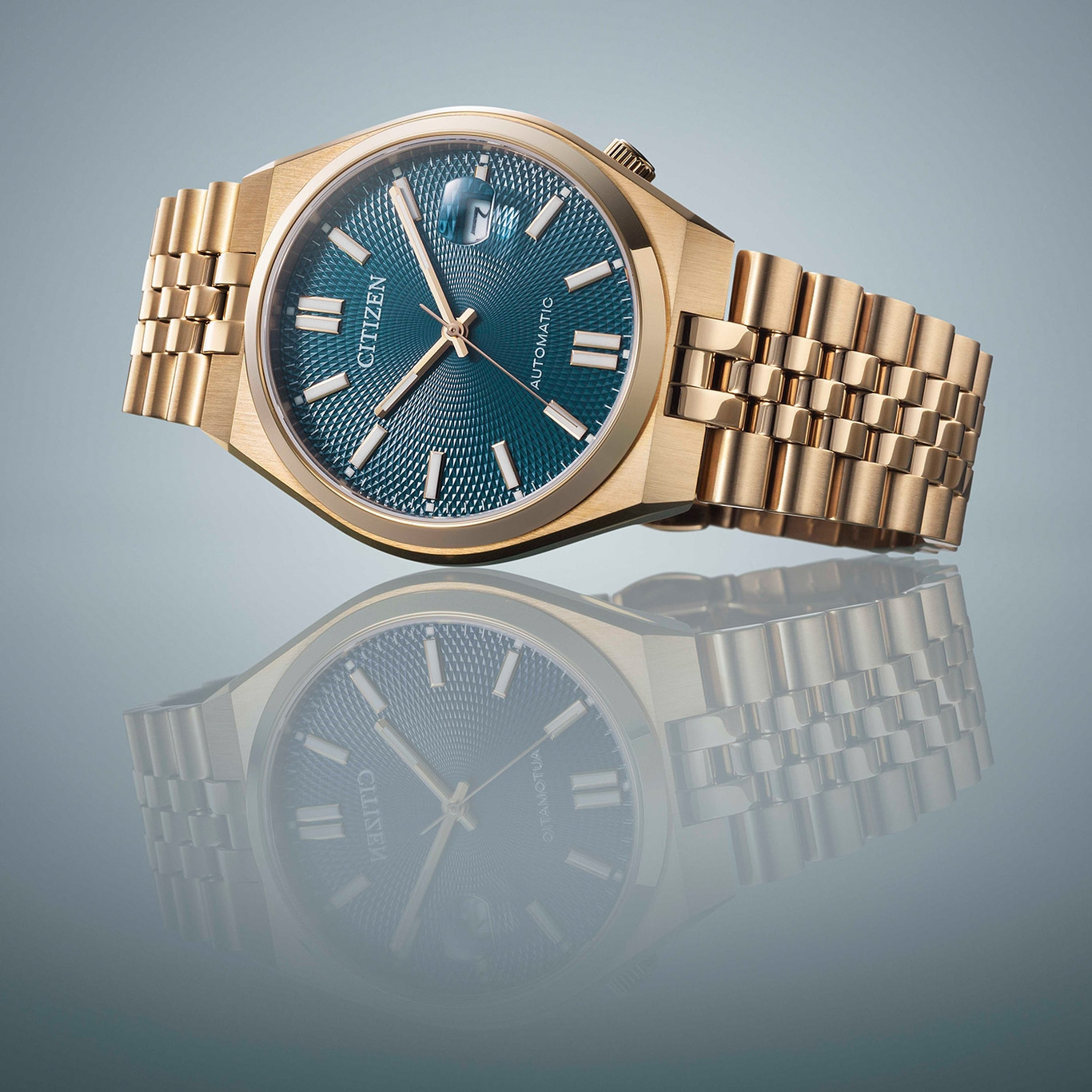 Gold Citizen watch with a blue face and reflection on a surface.
