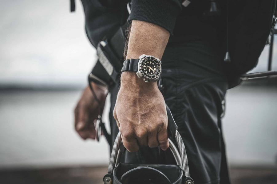 Man wearing a watch, holding equipment, close-up shot, black outfit