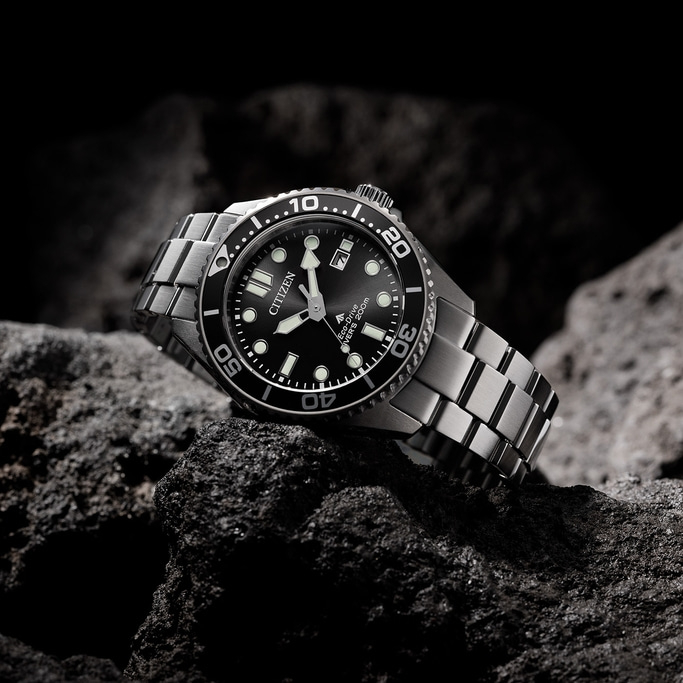 A Citizen watch on a rock. Black dial and silver bracelet.