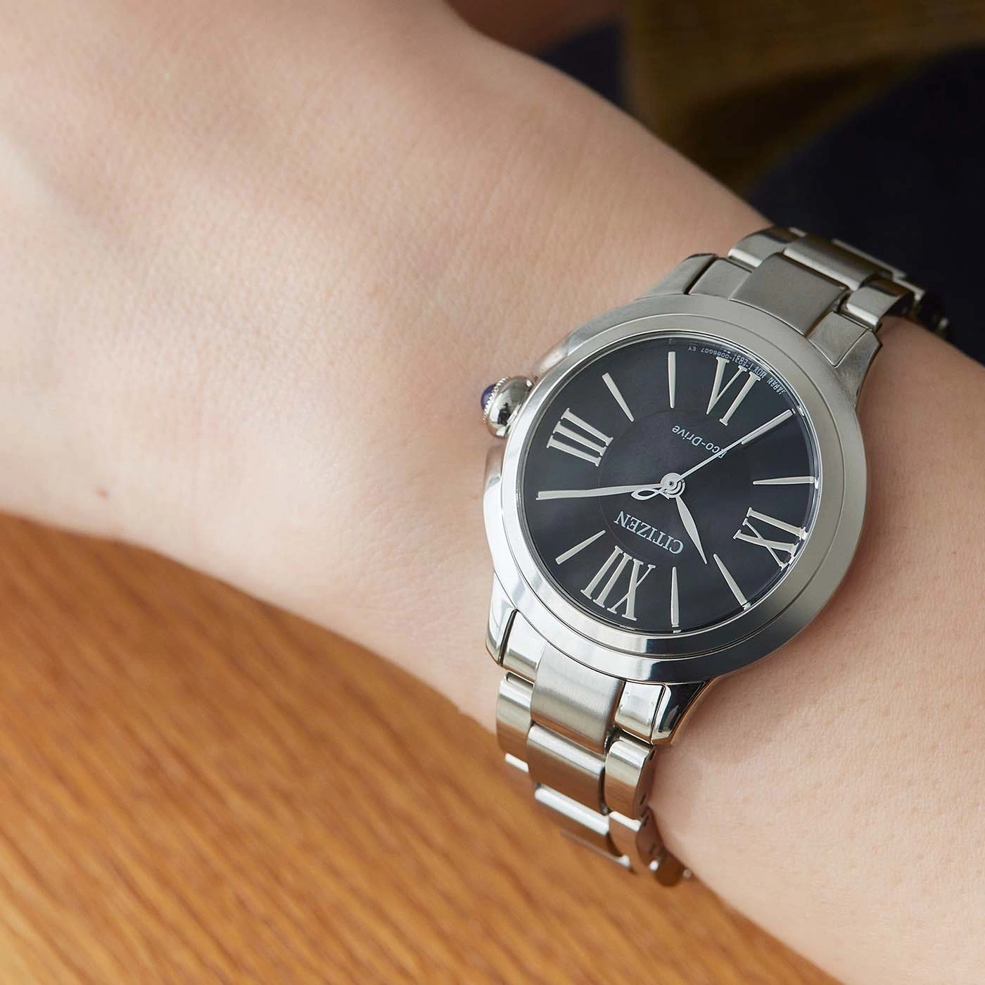 Citizen watch on wrist, black face, silver band, Roman numerals, Eco-Drive, close-up
