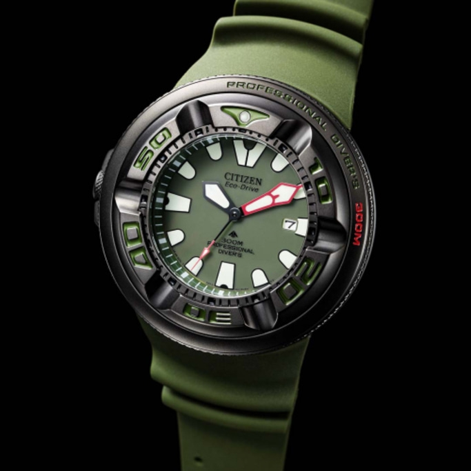 Citizen Eco-Drive watch with green strap and face, black background, close-up shot.