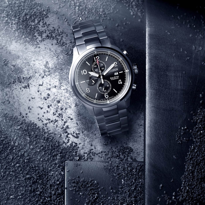 Citizen watch on a textured surface with black dial and titanium finish.