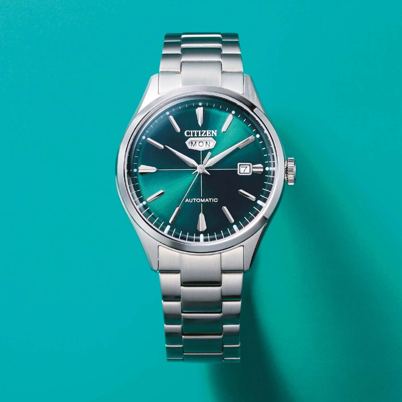 A close-up, top-down view of a silver Citizen watch with a green dial.